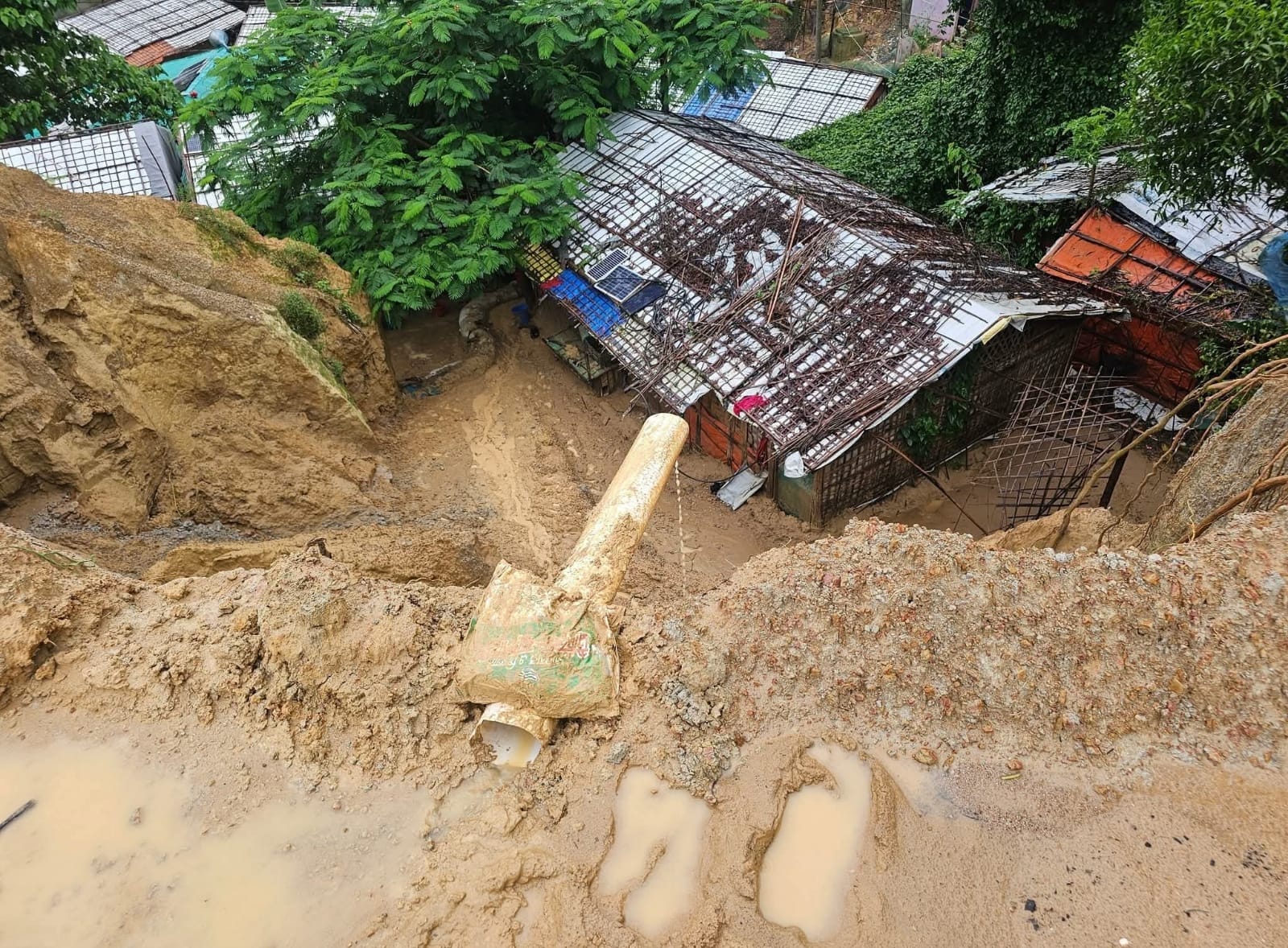 Rohingya refugees navigate floodwaters in Ukhiya refugee camp, where continuous heavy rains have submerged shelters and caused landslides, damaging hundreds of homes and displacing thousands. (Photo: V7N)